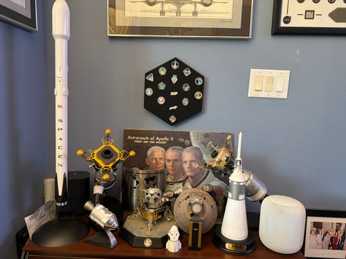 Reviewer's SpaceX Starship Flight Pin Collection on its display mount, hanging on a wall above other space memorabilia.
