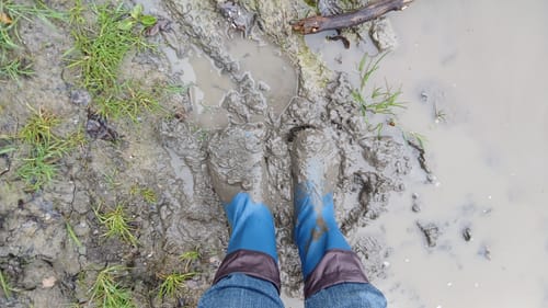 Rezensent testet die Brisk I Barfuß-Gummistiefel in tiefem, nassem Schlamm.