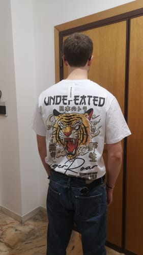 A reviewer seen from behind wearing the white Undefeated T-Shirt, showing the large tiger graphic on the back.