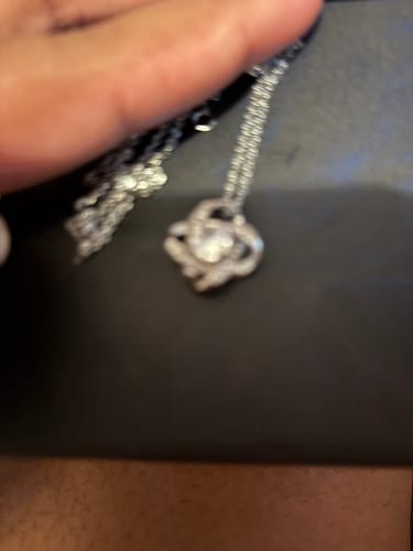 Blurry close-up of a customer holding the silver Love Knot Necklace.