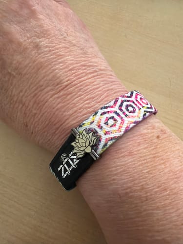 Customer wearing the You Are Enough Bracelet, showing the colorful patterned band and black clasp with a lotus flower charm.