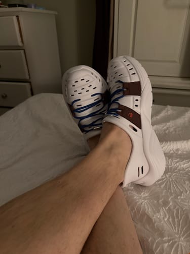 Customer relaxing with their feet up, wearing the white Early Bird Wildpools with blue laces indoors.