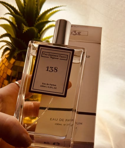 Reviewer holds the rectangular bottle of Inspired By Angels Share - 138 fragrance in front of its packaging.