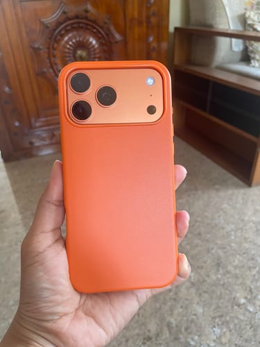 Customer holding the Ember Orange Signature Leather Magsafe Case in their hand.