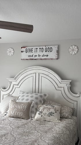 Customer's rustic "Give It to God and Go to Sleep" sign hanging on a bedroom wall above a decorative headboard.