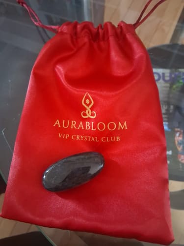 Customer's polished labradorite stone from the VIP Crystal Club, shown with its red branded pouch.