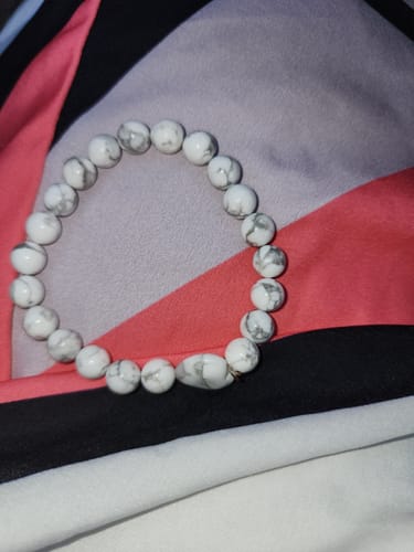 Reviewer's monthly crystal bracelet with round white beads that have grey marbling.