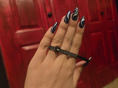 Customer using the black plastic RING SIZER to measure their finger size.