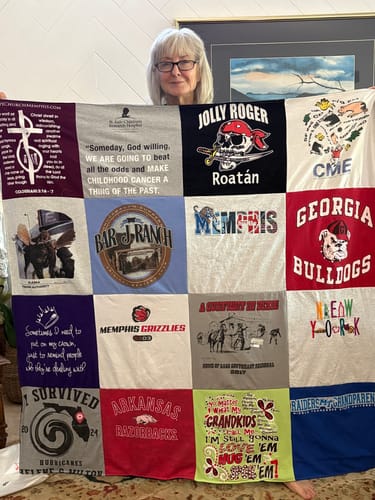Customer holding up her colorful Project Repat T-Shirt Quilt made from various t-shirt squares.