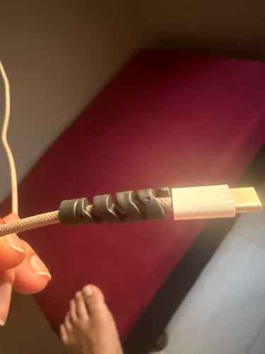 Close-up of a customer's hand holding a cable with the black cable protector attached near the connector.