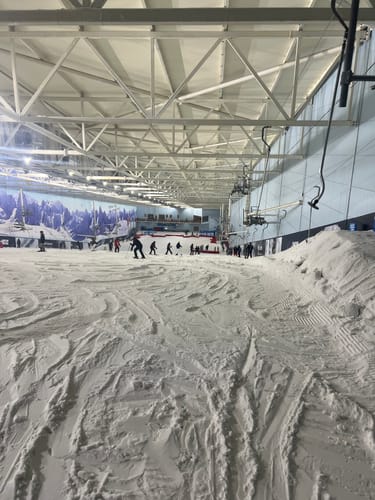 Reviewer's photo from an indoor ski slope, showing the environment for the Women's Coffee Baggy Snow Pants.