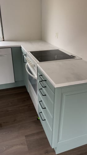 Nærbilde av kundens kjøkkenbenk med hvit mikrosement kontaktplast rundt platetoppen.
