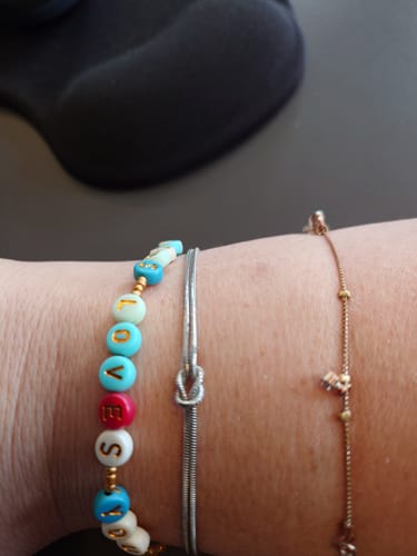 A customer's wrist wearing the silver Forever Knot Bracelet, shown between two other bracelets.