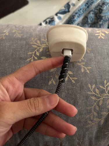 Customer showing a black spiral cable protector wrapped around a charging cable near the plug.