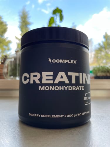 Customer's black tub of Complex Creatine Monohydrate resting on a surface indoors.