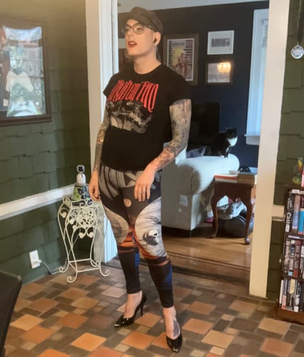 Reviewer wearing the Anthrax - Persistence of Time leggings with a band t-shirt and heels in their home.