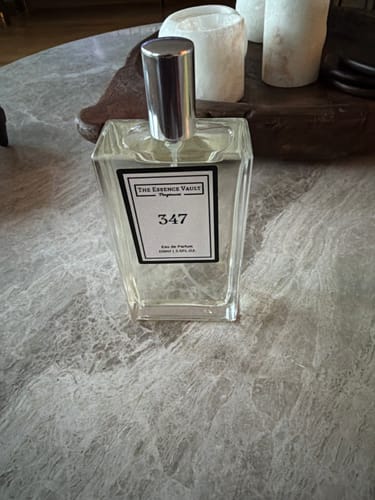 Customer's glass bottle of Inspired by Utopia Vanilla Coco - 347 perfume on a grey marble surface.