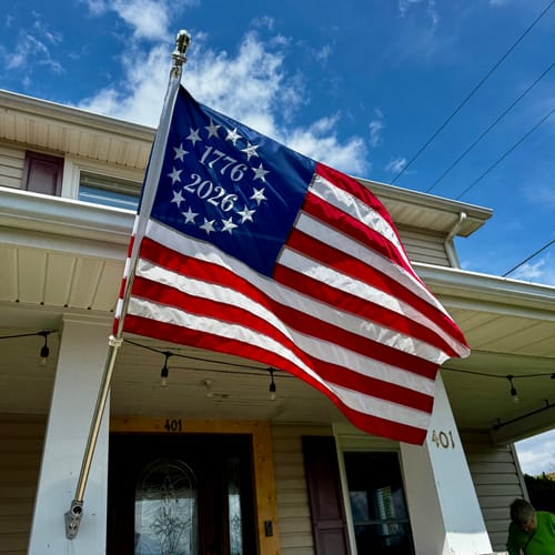 Customer's 1776 to 2026 Betsy Ross Flag waving on a flagpole attached to their house.