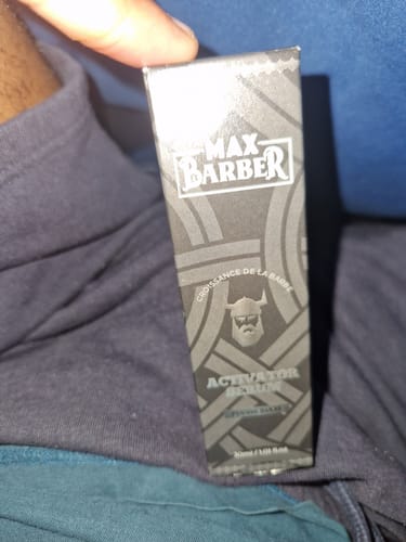 Un client tient la boîte du sérum Activator de Max Barber pour la barbe.