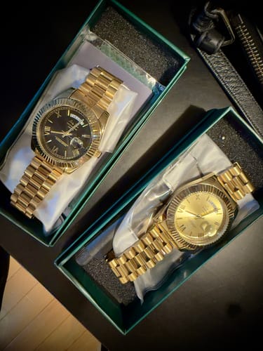 Customer showing two gold Lucky Fours® Santos watches in their open boxes, one with a black dial and one with a gold dial.