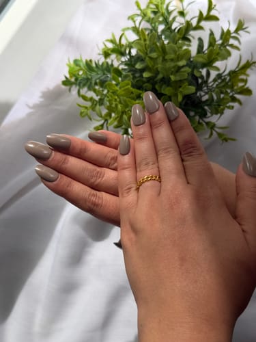 A reviewer's hand with taupe nails wearing the delicate gold Curb Chain Ring.