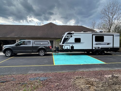 Reviewer's grey Ford F150 with the 3 Inch Rear Lift Kit, showing a level stance while towing a large travel trailer.
