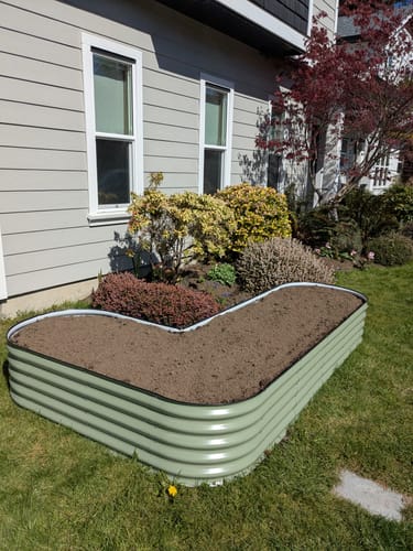 Reviewer's light green modular garden bed set up in an L-shape on a lawn and filled with fresh soil.