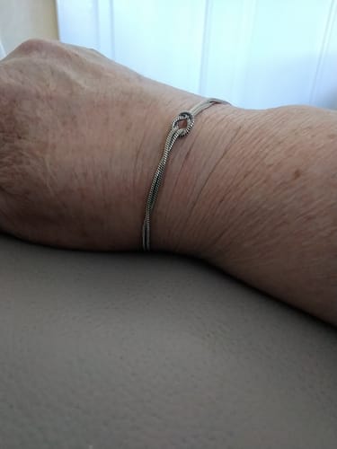 Close-up of a reviewer's wrist wearing the delicate Forever Knot Bracelet.