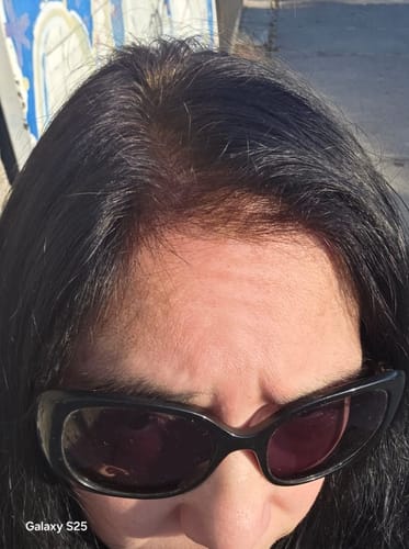 Primer plano del cabello de una clienta mostrando las raíces cobrizas cubiertas con Henna Jamila sobre cabello oscuro.