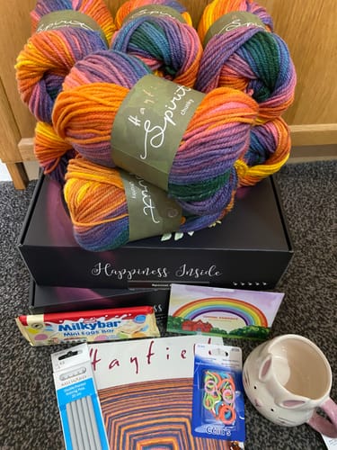 Reviewer's Chasing Rainbows Special Edition Blanket Box contents, including colourful yarn, treats, and knitting gifts.