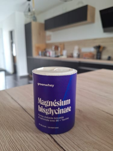 Avis d'un client montrant le pot de Magnésium Bisglycinate posé sur une table en bois.