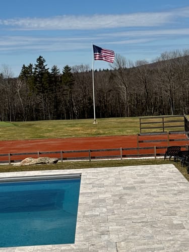 Reviewer's Heavy Duty American Nylon Flag waving on a flagpole in a large, open yard.