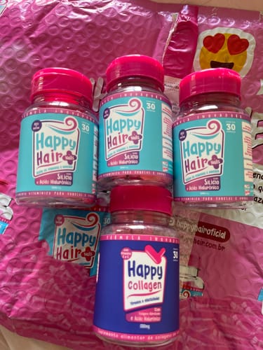 Cliente exibe três potes do suplemento Happy Hair e um pote de Happy Collagen em cima de uma embalagem rosa.