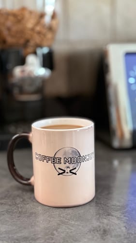 Reviewer's Coffee Moonjoy magic mug filled with a hot beverage, revealing the 'Coffee Moonjoy' design on a countertop.