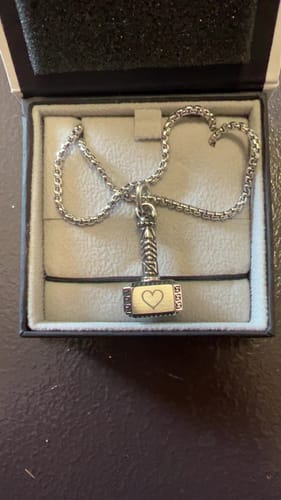 Customer's Hammer of Strength Urn Pendant in its gift box, showing the front engraving of a heart.