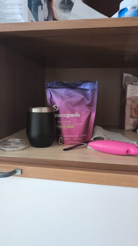Customer's Rainbow Dust starter kit, with the product bag and black mug displayed on a wooden shelf.