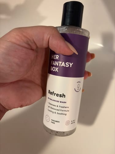 A customer holding the bottle of Refresh Plant Based Intimate Body Wash in their hand.