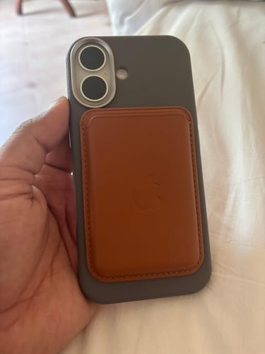 Customer holding a dark phone with the copper brown Signature Leather Magsafe Wallet attached.