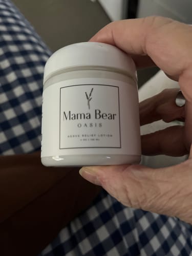 Customer holding a white jar of Mama Bear Nerve Relief Lotion, showing the product label.