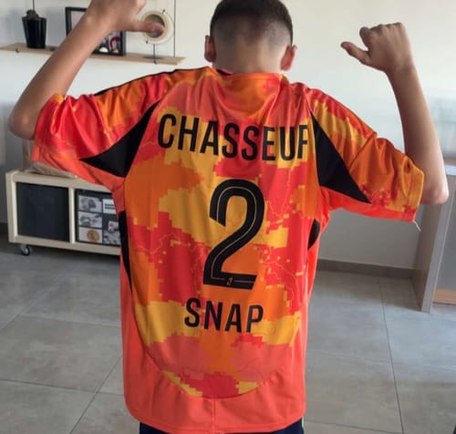 Client de dos portant son maillot Third du Paris FC orange, personnalisé avec un flocage.