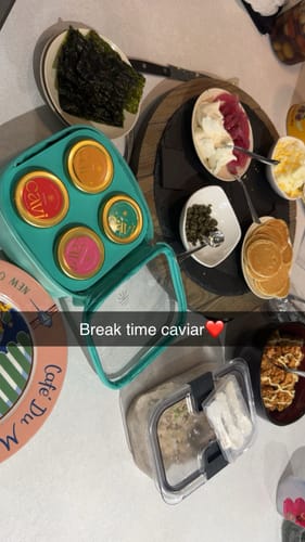 Customer's Cavi caviar jars in a turquoise container, displayed with mini pancakes and other delicious accompaniments.