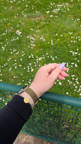 Customer wearing the gold Pet Portrait Bracelet with a round engraved pendant on their wrist outdoors.