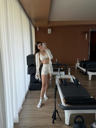 Reviewer in a studio wearing the cream Wrap Top tied at the front over a matching bra and shorts.