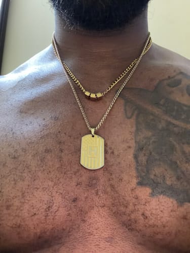 Close-up of a customer wearing two layered gold-tone necklaces against their chest.