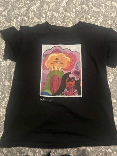 Customer's black Across the Pacific baby tee laid flat, showcasing the colorful graphic design on the front.