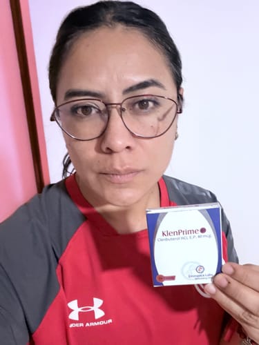 Una clienta sonríe mientras sostiene la caja de Klenprime Clenbuterol en su mano, mostrando el producto.