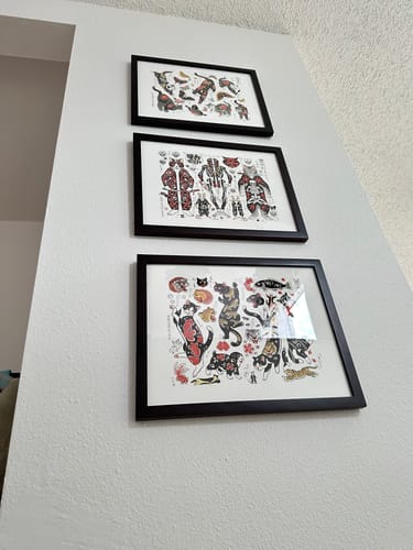 Reviewer's three framed art prints, including the Koi Cat Flash Print, hanging vertically on a white wall.