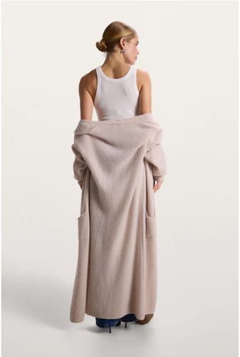 Reviewer from behind, wearing the beige Yasmin Open Cardigan draped off the shoulders to show its length.