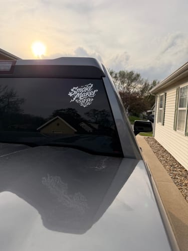 Customer's white Smoke Matters Decal applied to the back window of a truck at sunset.
