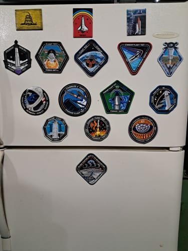 Customer's Artemis II patch displayed on a white refrigerator as part of a large space patch collection.